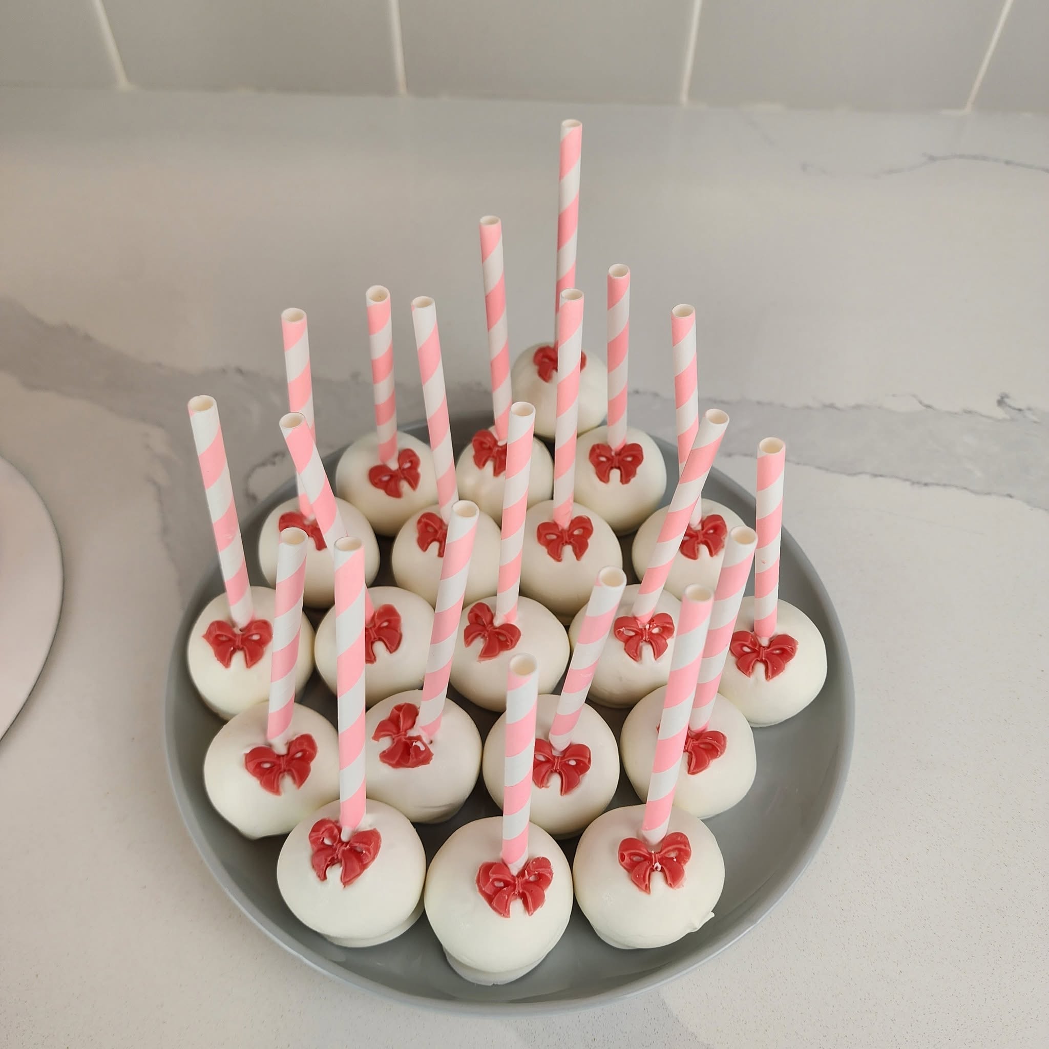 White cake pops decorated with pink bows