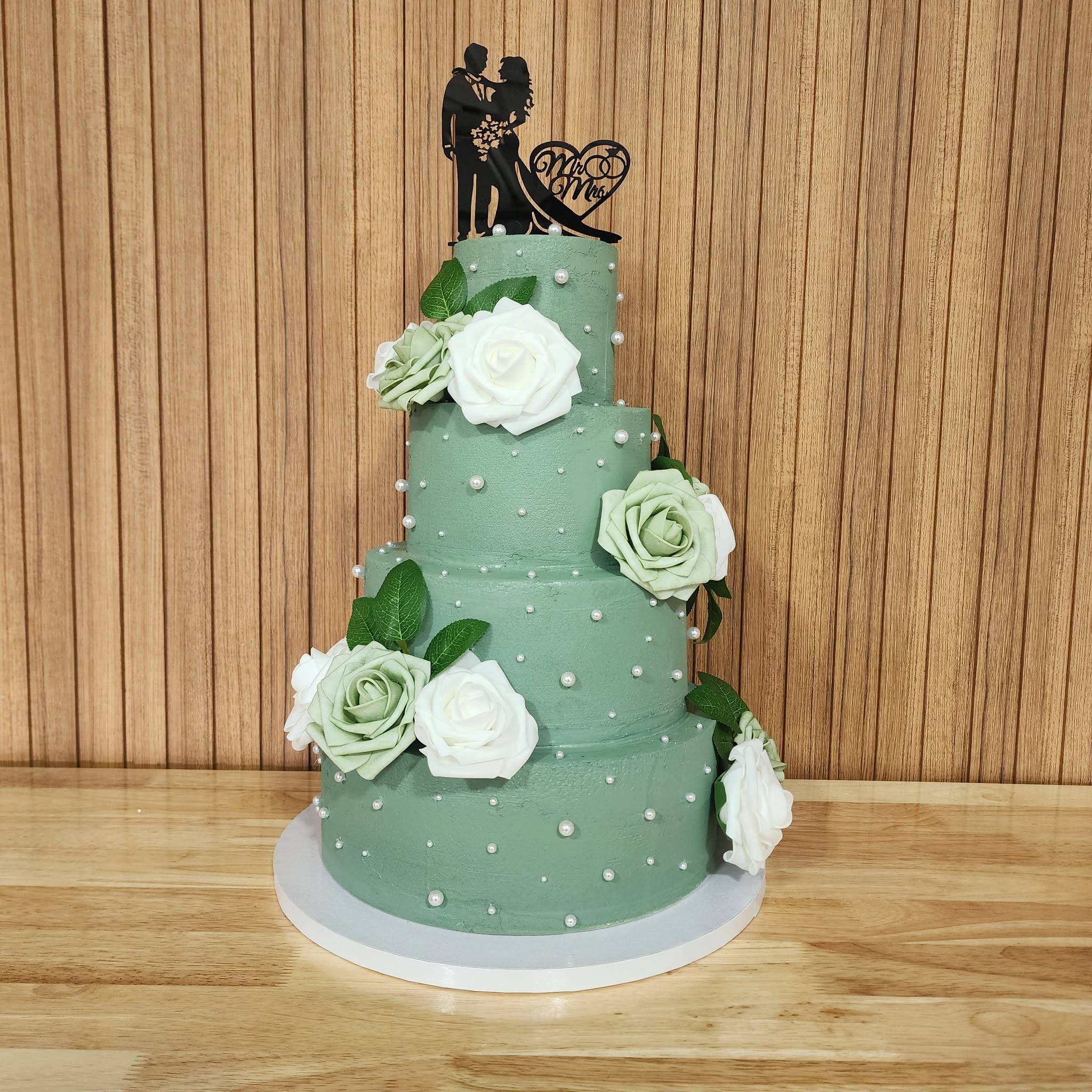 Four-tier sage green wedding cake with white roses and pearl details