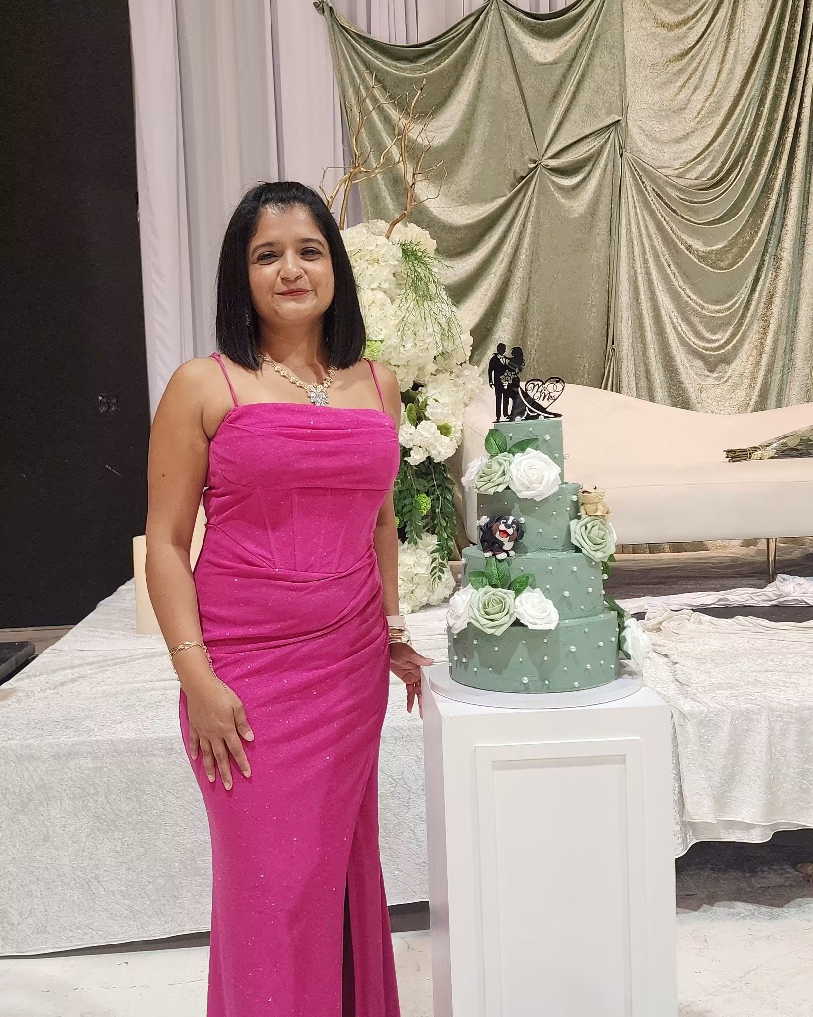 A four-tier sage green wedding cake decorated with white and green roses and pearl accents